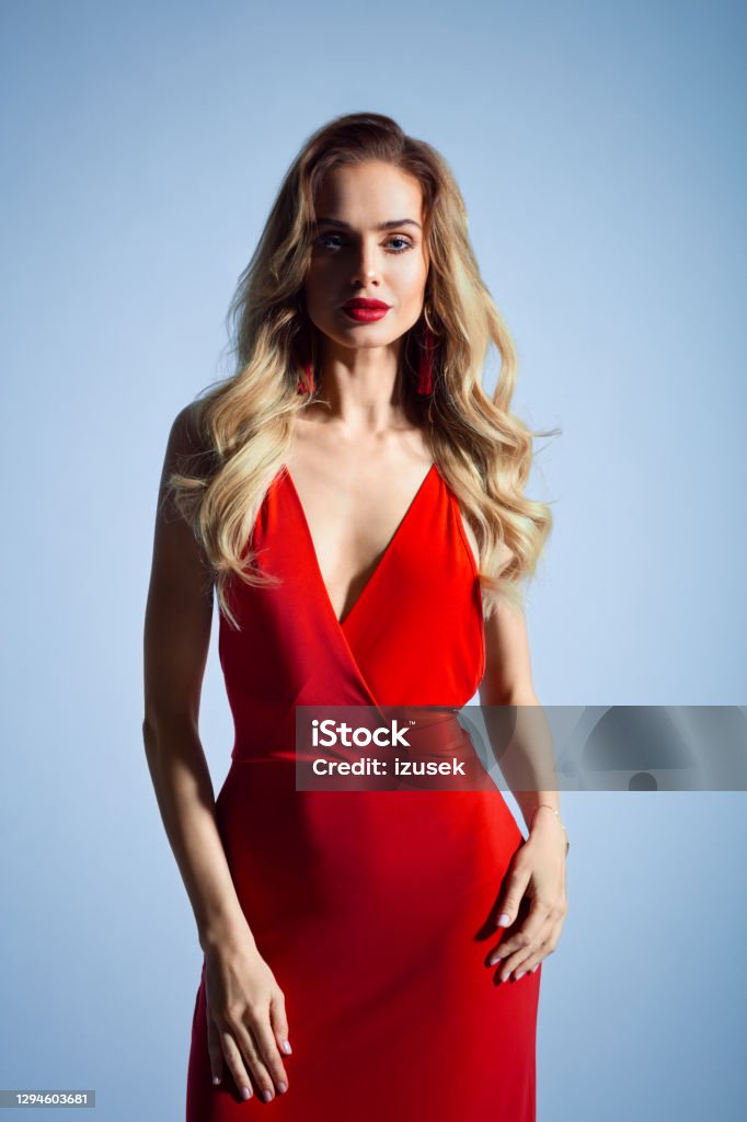 Beautiful woman in red dress Glamour portrait of beautiful long blond hair woman wearing red dress. Studio shot against grey background. 20-29 Years Stock Photo
