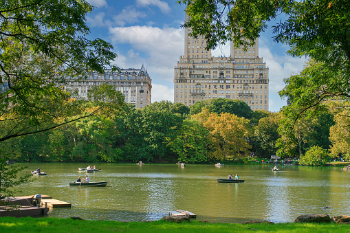 Central Park in Autumn Colors (Foliage), The Lake and The San Remo Coop Building, Manhattan, New York. The San Remo is a luxury 27-floor co-operative apartment building built in 1930 that is located at 145 Central Park West. The San Remo is now one of the most desirable and expensive apartment buildings in Manhattan.  Recent asking prices have ranged from a minimum of $3 million to a high of $75 million. Tourists are enjoying rowboats on the lake.