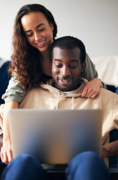 istock Relaxed Young Couple At Home Sitting On Sofa Browsing Internet On Laptop Computer 1294604827