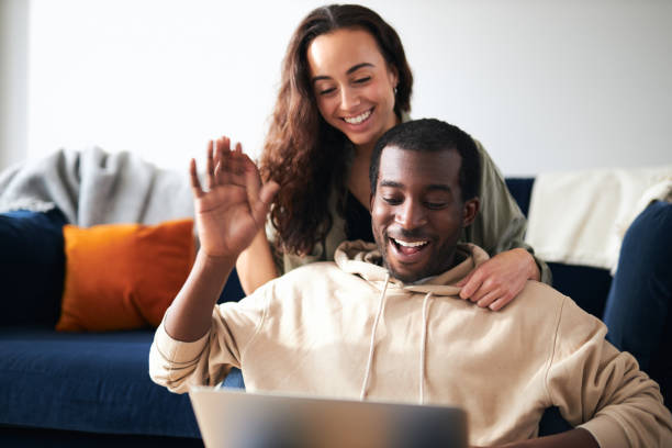 istock Relaxed Young Couple At Home Sitting On Sofa Making Video Call On Laptop Computer 1294604834