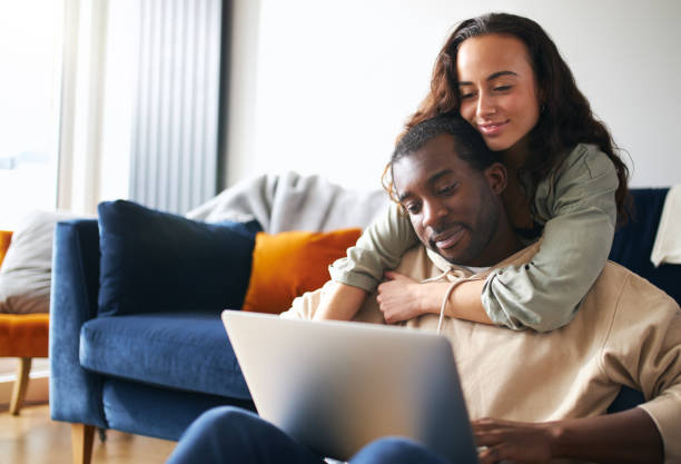 istock Relaxed Young Couple At Home Sitting On Sofa Browsing Internet On Laptop Computer 1294604839