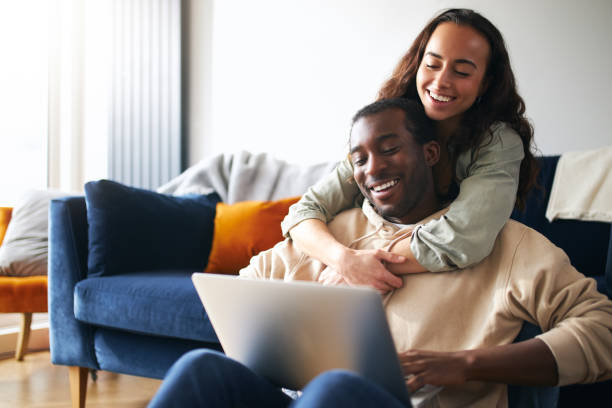 istock Relaxed Young Couple At Home Sitting On Sofa Browsing Internet On Laptop Computer 1294604845