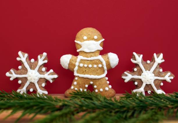 istock Gingerbread man with protective face mask, snowflakes and spruce twig 1294606183