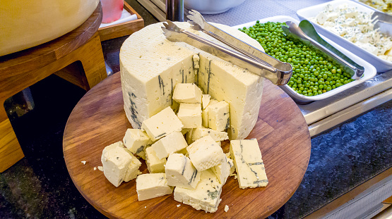 Photo of orgonzola cheese over a salad buffet.