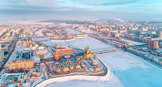 The Orthodox church of the city and brick buildings at the city embankment. Aerial view,sunny morning, winter, city center. Volga region, Russia