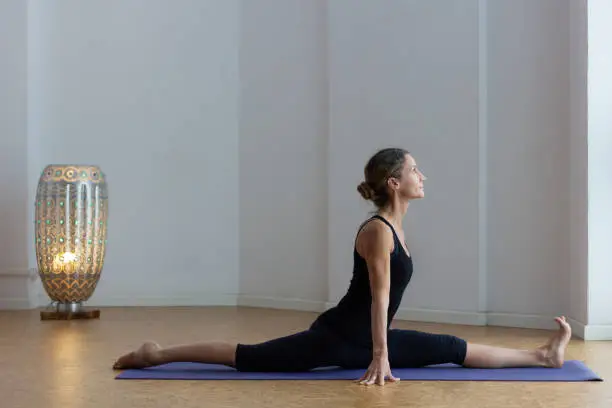 Photo of Flexible woman with split legs on monkey pose at studio