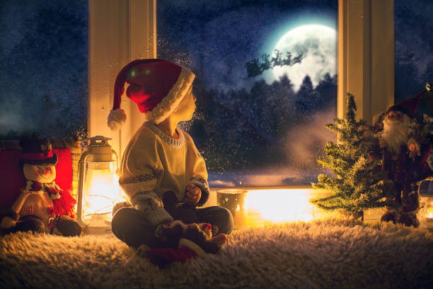 słodkie dziecko, siedzące na oknie, patrzące na zewnątrz dla świętego mikołaja - blizzard house storm snow zdjęcia i obrazy z banku zdjęć