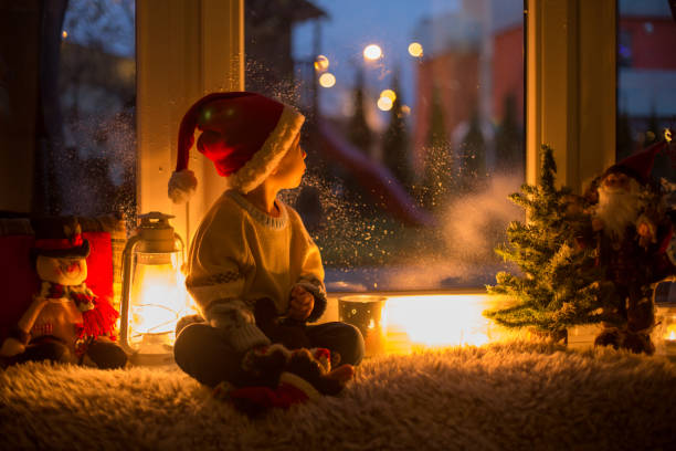 słodkie dziecko, siedzące na oknie, patrzące na zewnątrz dla świętego mikołaja - blizzard house storm snow zdjęcia i obrazy z banku zdjęć