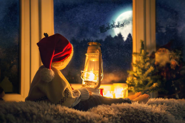 istock Cute child, sitting on a window, looking outdoors for Santa Claus 1294609982