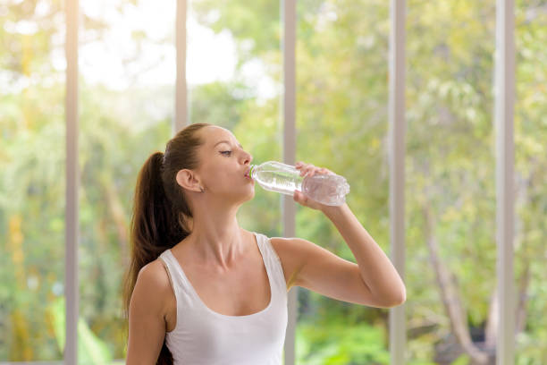 istock Fitness woman drinking water from bottle. Taking a break during training at gym with copy space 1294612309