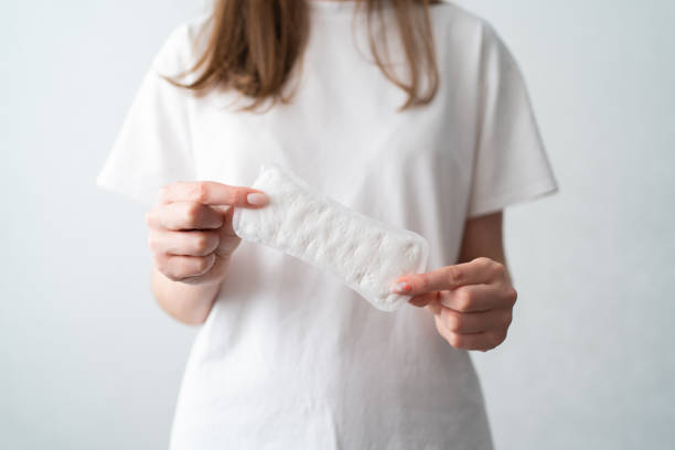 A woman with a period holds a white pad. Taking care of women's health. Hygiene during menstruation A woman with a period holds a white pad. Taking care of women's health. Hygiene during menstruation. sanitary napkin stock pictures, royalty-free photos & images
