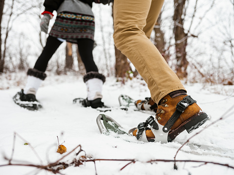 Close up of feet of  couple tracking with snowshoes, outdoor activity in winter.
