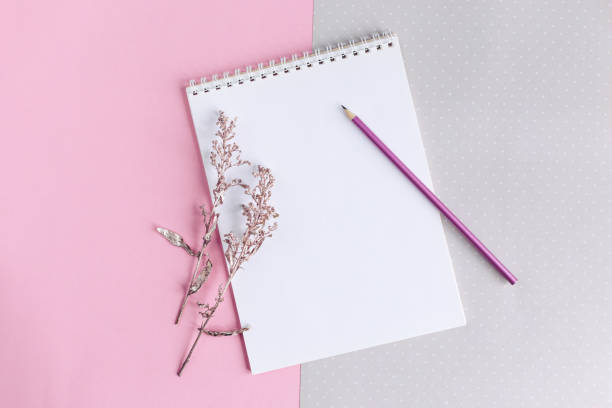 istock Notebook with blank page and pencil on a pink and grey background. 1294625845