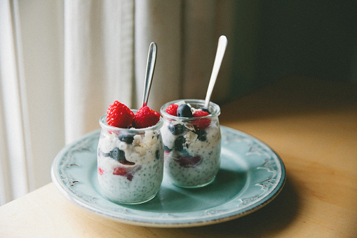 Chia seed pudding made up of coconut milk, maple syrup, chia seeds, raspberries, blueberries and coconut shavings for a healthy snack