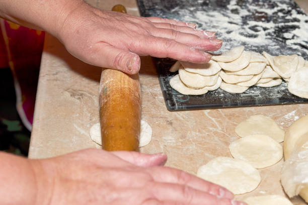 istock Hands with a wooden rolling pin roll out the dough on the kitchen table for making dumplings 1294634569