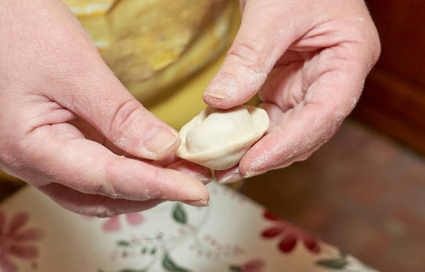 istock Hands soiled with flour hold a raw dumpling. Cooking homemade dumplings 1294634603