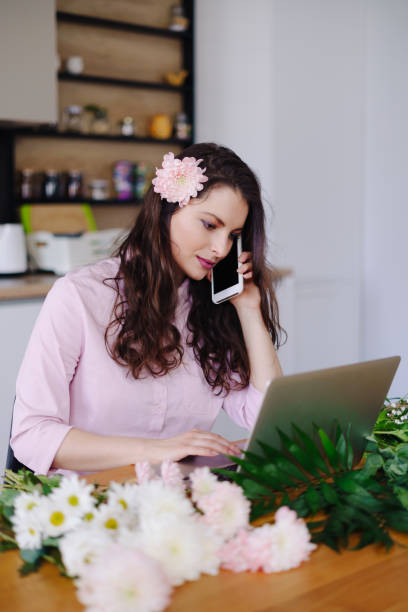 istock Young florist looking at laptop and answering phone call 1294636751