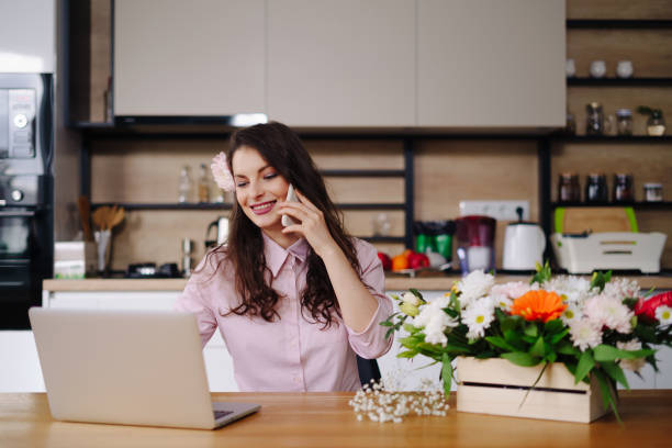 istock Young florist looking at laptop and answering phone call 1294636800