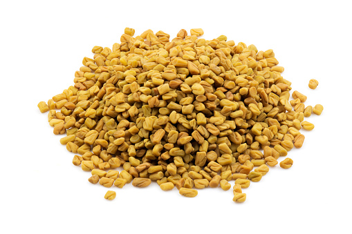 Heap of fenugreek seeds on a white isolated background