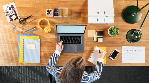 istock Top view of female student working on computer at desk at home. 1294641495