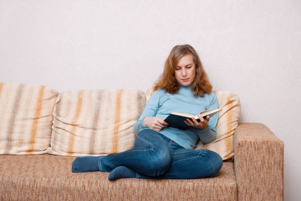 istock Woman sitting at home on the sofa and reading a book 1294642332