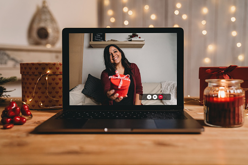 Young woman giving a present for Valentine's day during a videocall. Social distancing concept.
