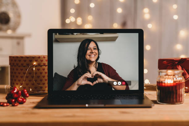istock Young woman doing an heart shape with hands for Valentine's day during a videocall 1294643121