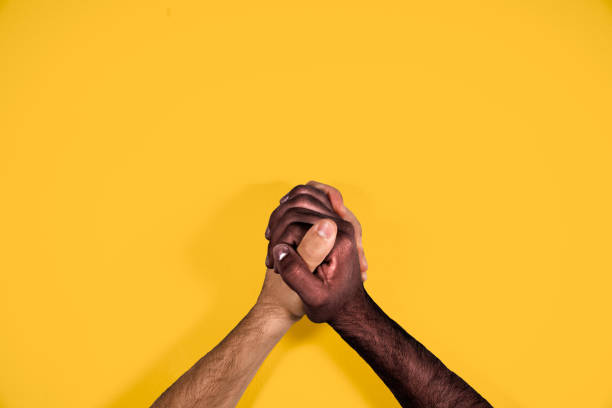 Multicultural hands united calling for freedom and equality on a yellow background. African and caucasian hands together calling for stop racism. Multicultural hands united calling for freedom and equality on a yellow background. African and caucasian hands together calling for stop racism. i cant breathe stock pictures, royalty-free photos & images