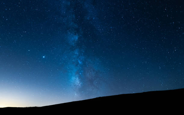 istock Milky way up a hill in a starry night sky. Blue sky with stars without light pollution. 1294647699