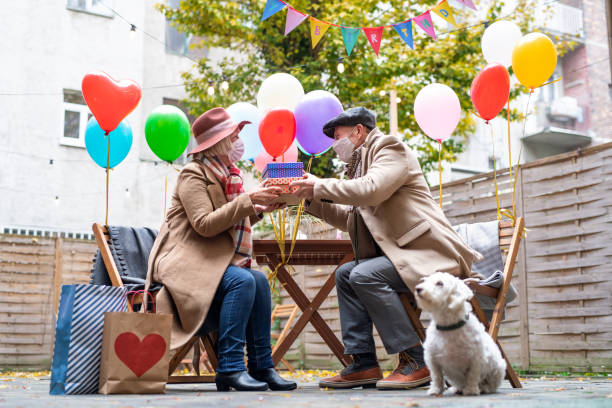 partenaires aînés heureux dans le café extérieur dans la ville, couples célébrant l’anniversaire. concept de coronavirus. - men giving balloon women photos et images de collection