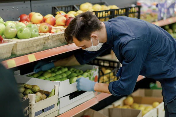 istock man in a protective mask standing near the counter with apples 1294656719