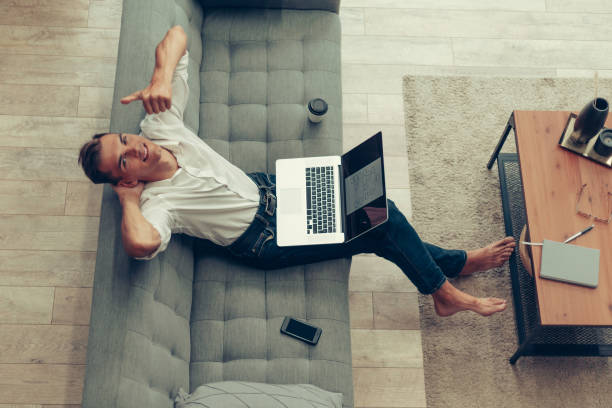 istock young man sitting on the couch and giving a thumbs up 1294657944