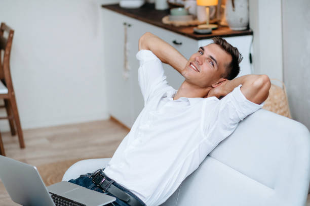 istock dreaming young man with a laptop sitting on the couch 1294658083