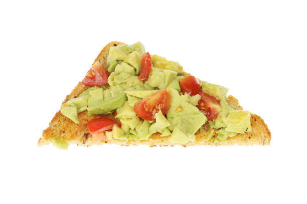 Avocado toast Smashed avocado and tomatoes on a triangle of toast isolated against white granary toast stock pictures, royalty-free photos & images