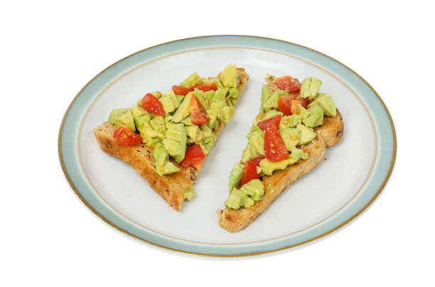 Crushed avocado Crushed avaocado and tomato on toast on a plate isolated against white granary toast stock pictures, royalty-free photos & images