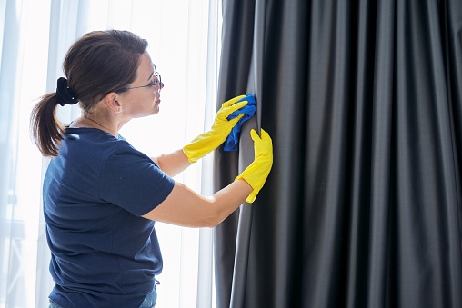 House cleaning, woman in gloves with a rag cleaning curtains. Housework, housekeeping, household, cleanliness concept