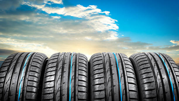 summer car tires on over blue sky with clouds. tire stack background. car tyre protector close up. black rubber tire. brand new car tires. close up black tyre profile. car tires in a row - speed horizontal commercial land vehicle automobile industry imagens e fotografias de stock