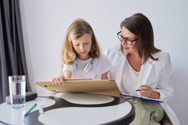 Professional family psychologist helping child, teacher social worker talking to a girl Professional family psychologist helping child, female teacher, social worker talking to a girl in office. Mental health, education training class, psychology, childhood physical therapist photos stock pictures, royalty-free photos & images