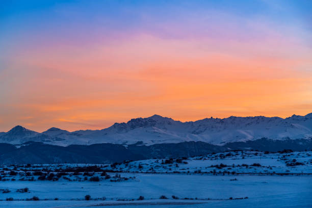 Photo of Beautiful panoramic sunset over the mountains and  snow-covered hills.