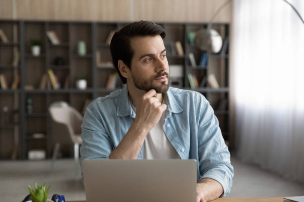 istock Pensive Caucasian man work on computer looking in distance 1294670614