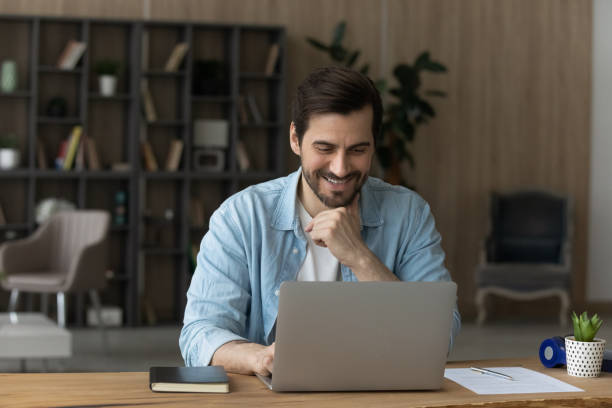 istock Smiling man look at laptop screen working online 1294670618