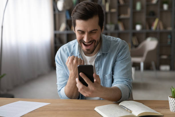 istock Overjoyed man triumph winning lottery on cellphone 1294670653