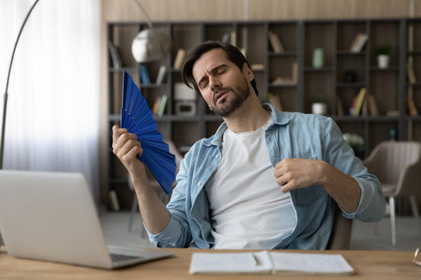 homem cansado sofre de onda de tempo quente com ventilador de mão - office fan - fotografias e filmes do acervo