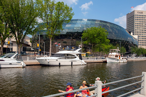 Ottawa, Canada - August 4, 2012: People paddle on the Rideau Canal with the Shaw Centre, a convention center in the background.