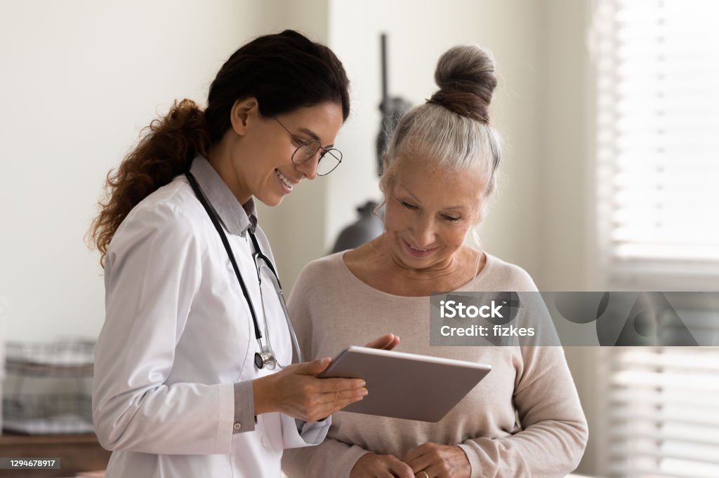 Happy doctor and senior patient use tablet at consultation - Royalty-free Doutor Foto de stock