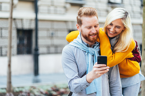 Happy young couple using a smartphone outdoor in the city