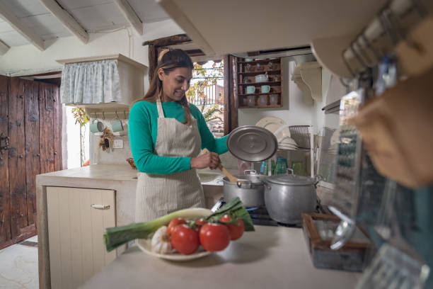 woman in a traditional vintage kitchen making a meal with old pots and vegetables focus on hands stock photo