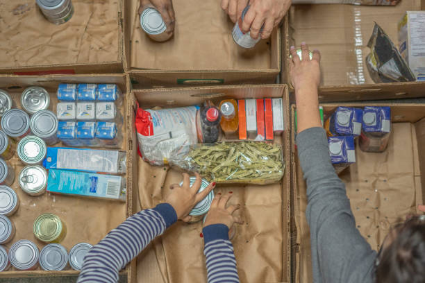 voluntarios en un banco de alimentos - hambriento fotografías e imágenes de stock