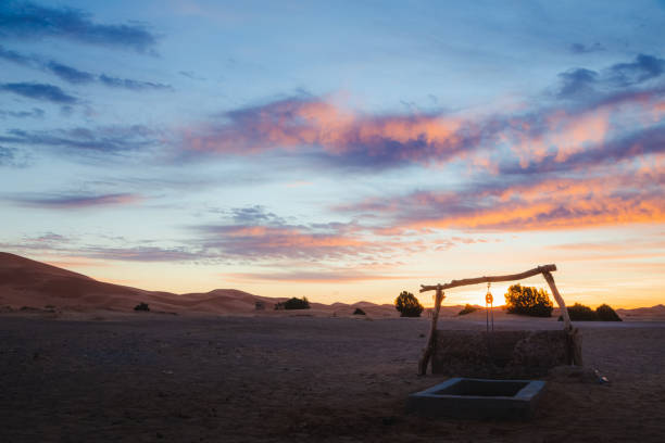 A sunrise view of a traditional water well and the desert sand dunes of Erg Chebbi from the village of Merzouga.