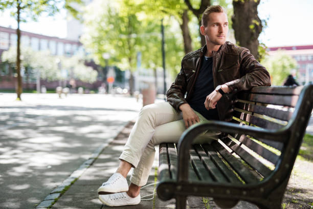 handsome man sitting down outside - casaco de couro imagens e fotografias de stock